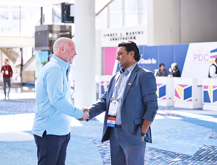 two conference attendees shaking hands in the registration area