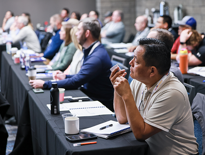 conference attendees sitting at tables taking notes in a session