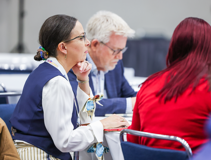 conference attendees sitting at a table taking notes in a session