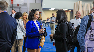 two attendees talking surrounded by people talking in exhibit hall