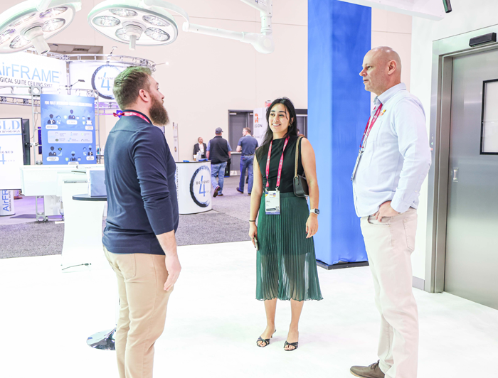 three conference attendees discuss healthcare environment solutions in the exhibit hall