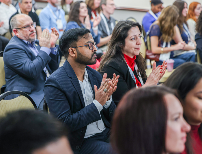 an audience of conference attendees applaud after a student challenge presentation